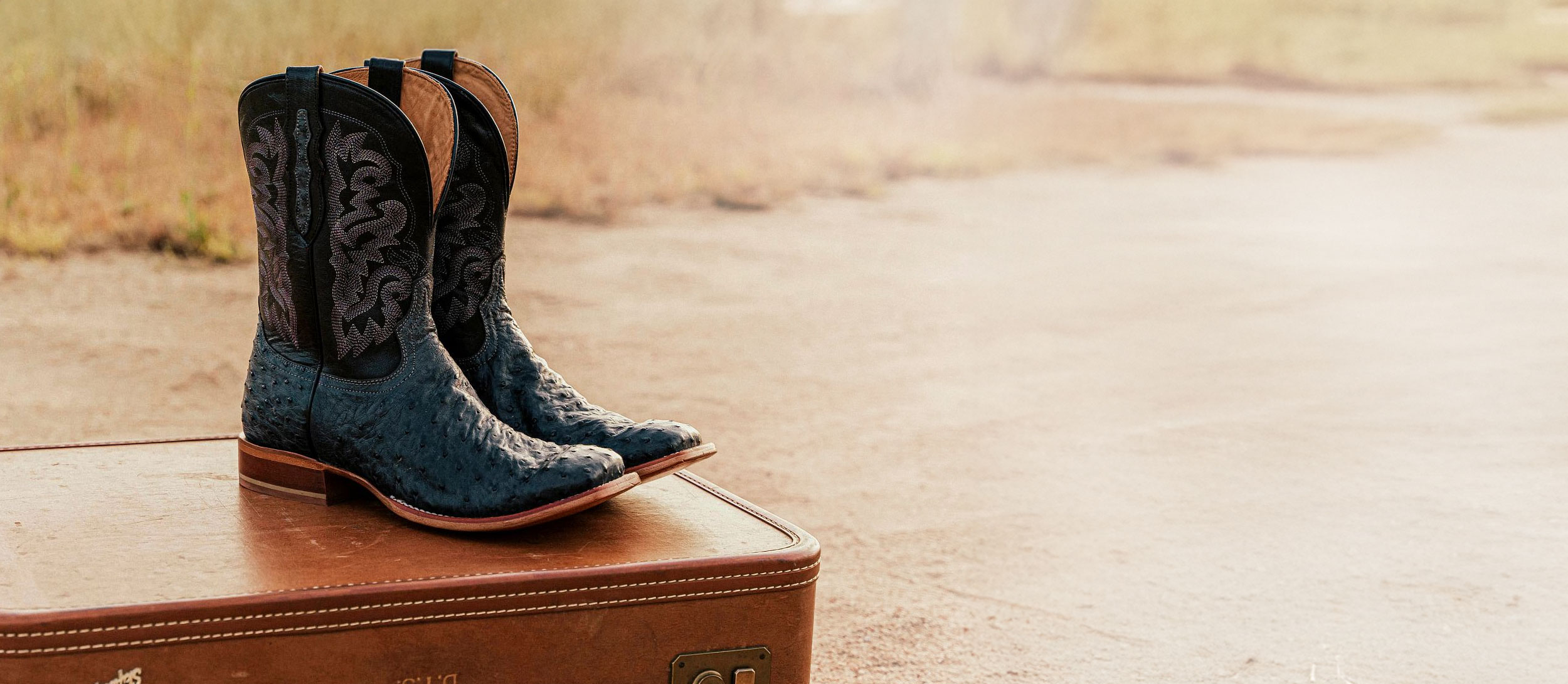 A pair of the Moore 11" Full Quill in Grey sitting on a leather suitcase.